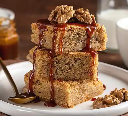 Teller mit Stapel von Blondies mit Walnüssen und Karamelsauce.