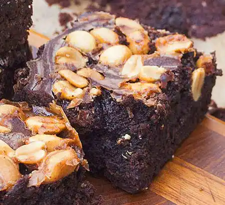 Teller mit Brownie mit Topping aus Erdnüssen und Karamelsauce.