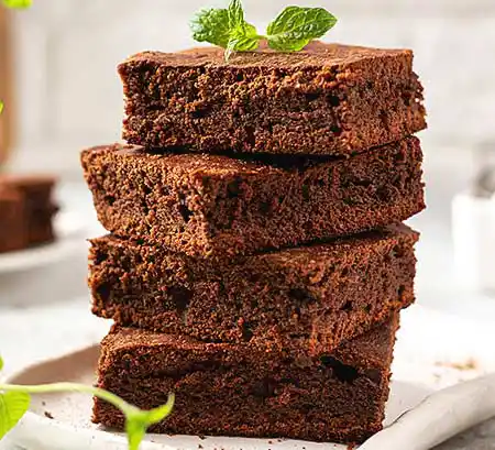 Teller mit gestapelten Brownies und Minzgarnitur.