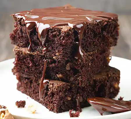 GTeller mit 3 Brownies und Schokosauce darüber.