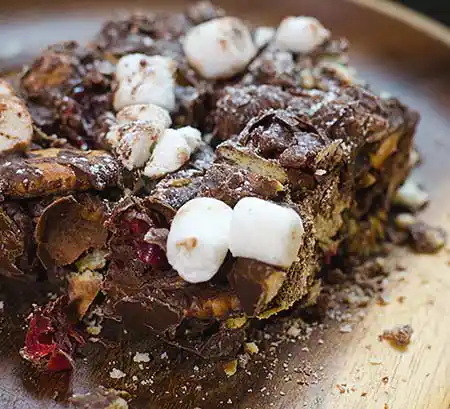 Brownie auf Teller mit Füllung aus Cookiebrösel und Marshmellow-Topping.