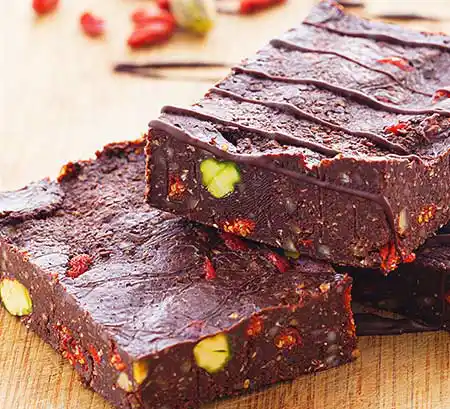 Teller mit pikantem, veganem Brownie mit Pistazien und Gojibeeren.