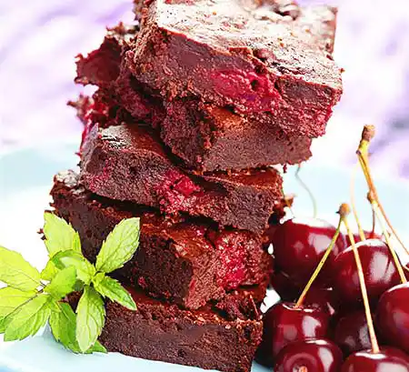 Stapel von Brownies mit Füllung aus Kirschen und Minzgarnitur.