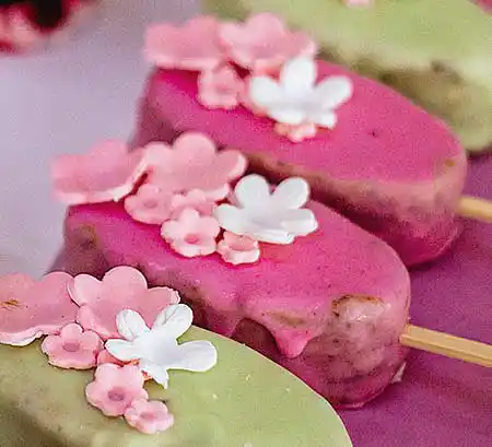 Rote und grüne Cakesicles mit Marzipan-Blüten.