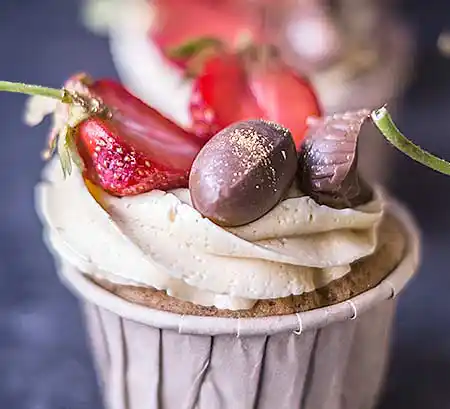 Cupcake mit Buttercreme Topping im Swirl Look, Schoko Bons und Erdbeeren als Topping.