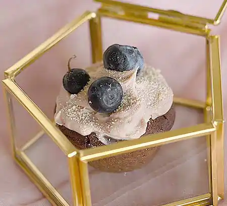 Cupcake in Glasvitrine mit Blaubeere als Topping.