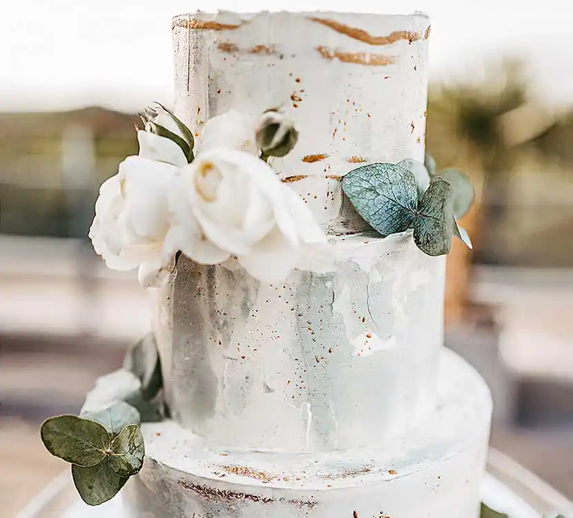 3-stöckige weiß-grüne Hochzeitstorte mit Goldsprenkel und Blumendekor.