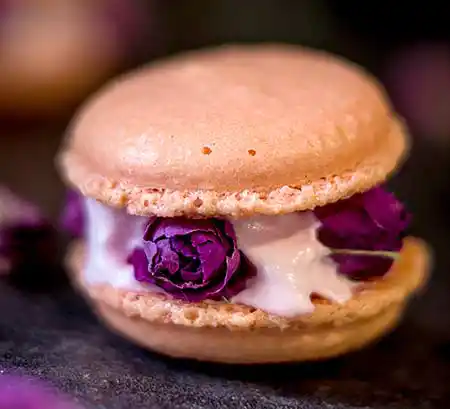 Macaron mit kleinen roten Rosen als Deko aus Holztisch.