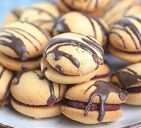 Helle Macarons mit Weincremefüllung und Topping aus Schokosauce.