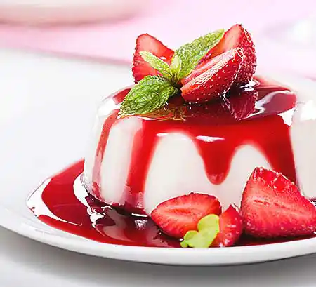 Teller mit frisch gestürzte Panna Cotta aus gekochter Sahne mit frischer Vanille und Erdbeeren.