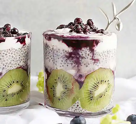 Gläser mit Sahne-Mousse mit Chiasamen, frischer Kiwi und einem feinen Blaubeerragout.