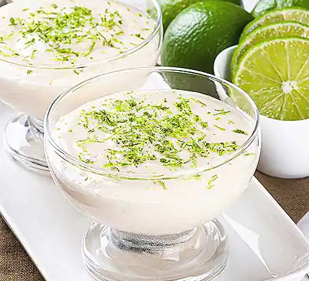 Gläser mit weißem Schokomousse mit frischer Crème aus Limette und geschlagener Sahne.