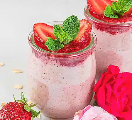 Gläser mit Amarettini-Erdbeercreme mit Mandelkeksen auf weißem Schokomousse mit Minze.