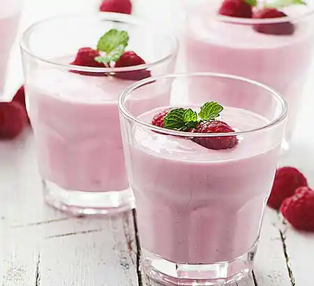 Gläser mit Himbeer-Joghurt-Mousse mit geschlagener Sahne und frischen Himbeeren.