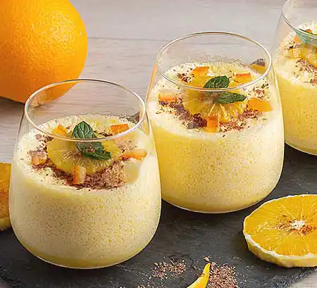 Gläser mit Joghurt-Mousse mit frischem Organgen-Pudding, karamellisierten Nüssen und Orangenscheiben.