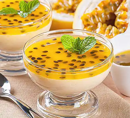 Gläser mit weißes Schokomousse mit einem Spiegel aus frischen Passionsfrüchten und Minzgarnitur.