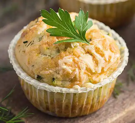 Muffin mit Zucchini und Käse auf Holzbrett.