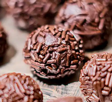 Dunkelbraune Rumkugeln auf Holztisch.