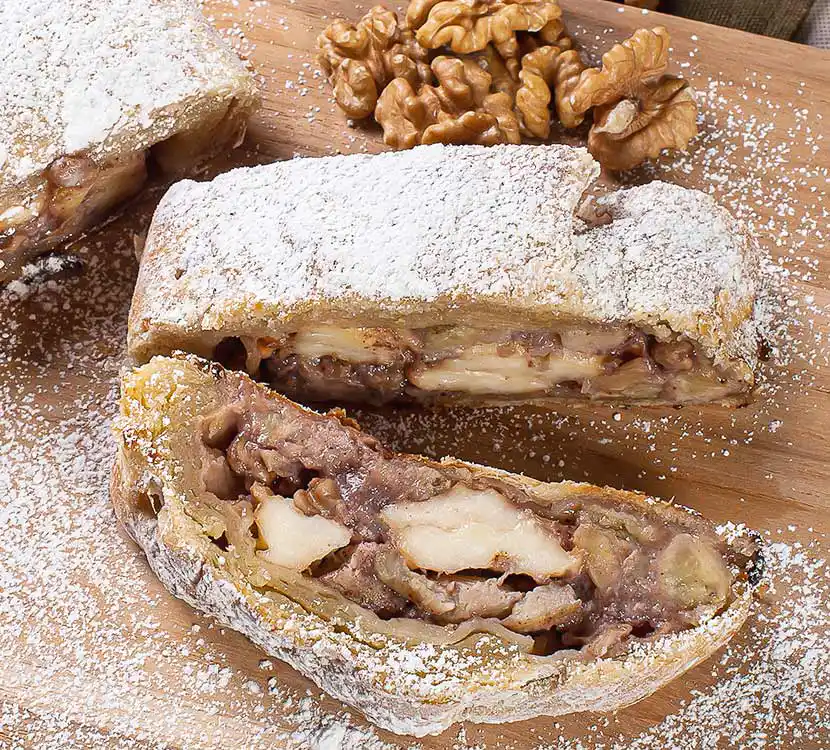 Angeschnittener Aofelstrudel mit Walnüssen auf Teller.