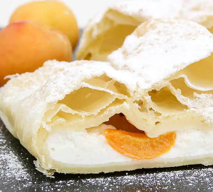 Stück Marillen-Topfenstrudel auf Teller.