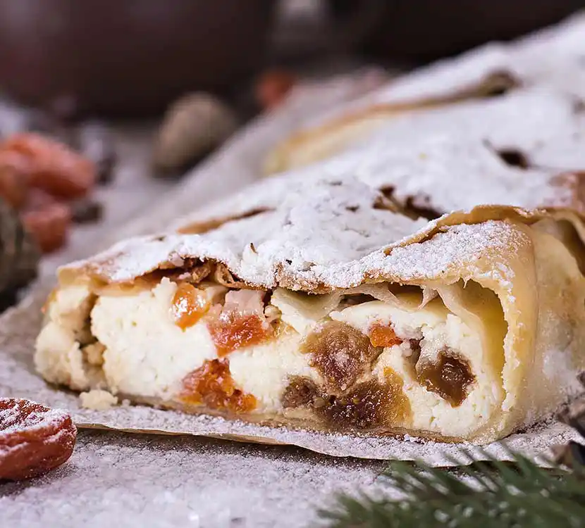 Mehrere Stücke Topfenstrudel mit Früchten auf Tisch.