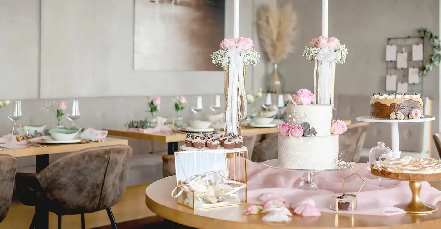 Gedeckte Tische mit Hochzeitstorte, Torte, Tartes Cupcakes und Dekoration Rosen.