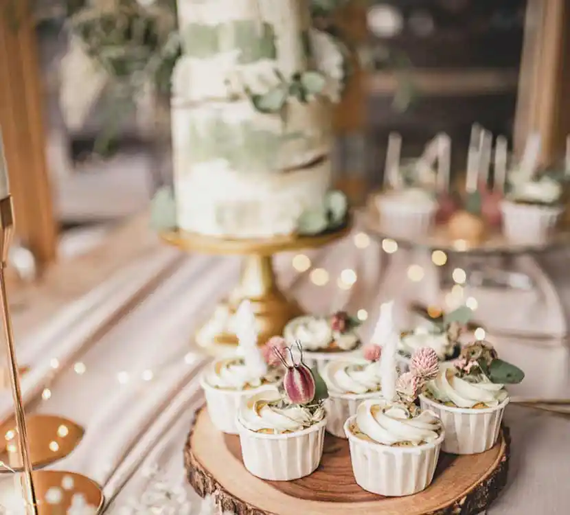 Gedeckter Tisch mit Hochzeitstorte, Cupcakes und Cakepops auf Teller im Bohostil.