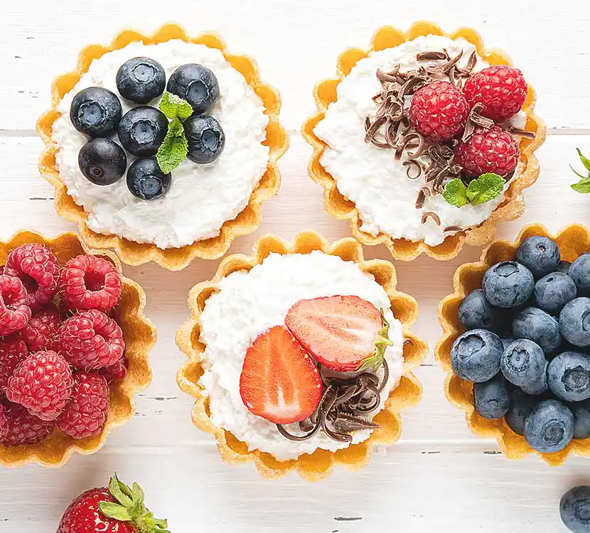 Mehrere kleine Kuchen mit Beeren darauf.
