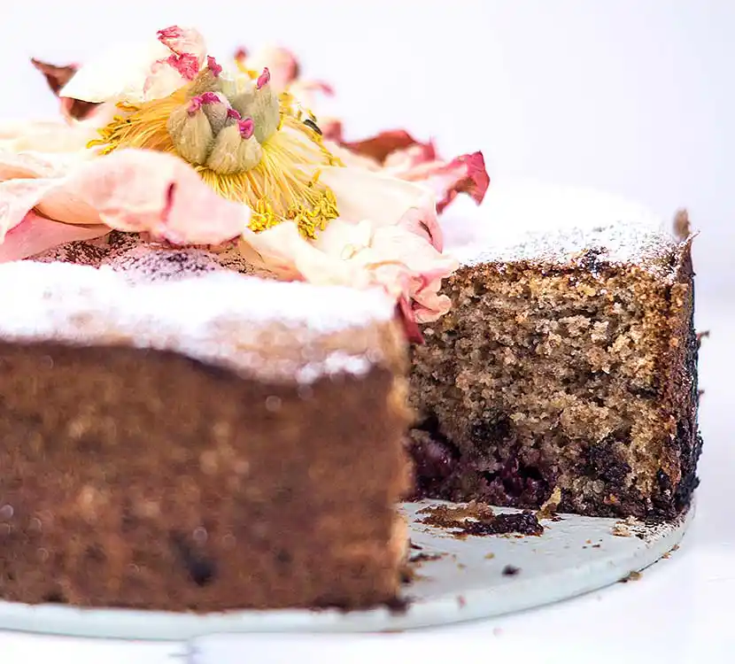 Teller mit angeschnittenem Kirsch-Nusskuchen mit Schokoladen-Stückchen.