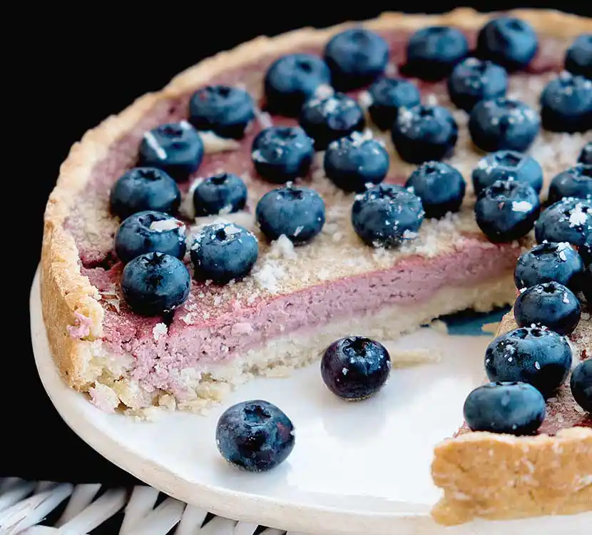 Teller mit angeschnittenem Kuchen mit Beerenmousse-Füllung.