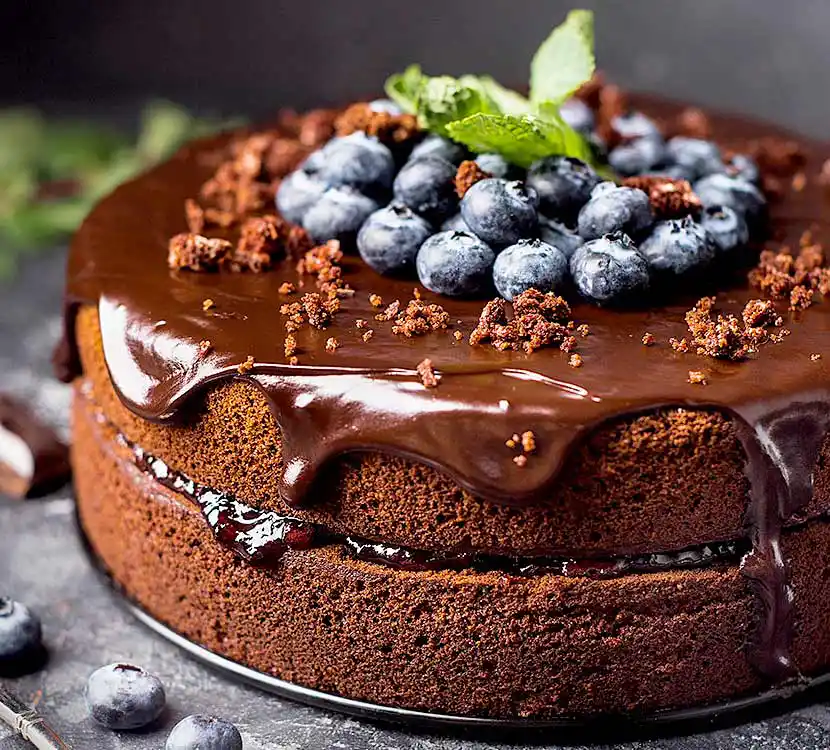 Tisch mit Schokokuchen, Schokosauce und Blaubeeren.