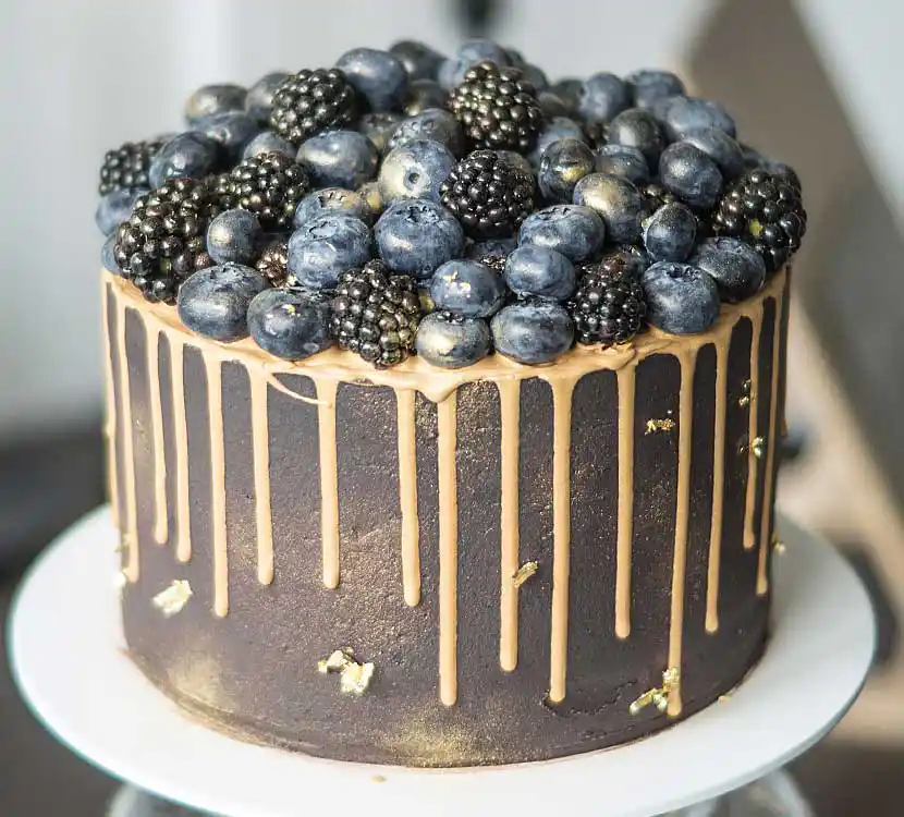 Dunkle Torte mit Gold-Drip und Beeren-Topping.