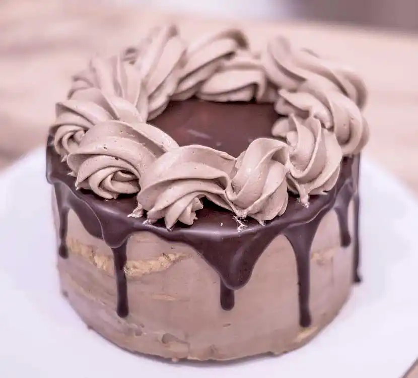 Helle Torte mit Schoko-Drip und Buttercreme-Deko.