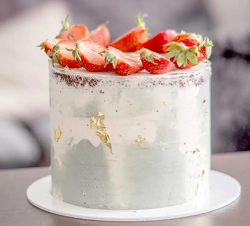 Teller mit weiß-grüner Semi Naked Torte und Erdbeeren.