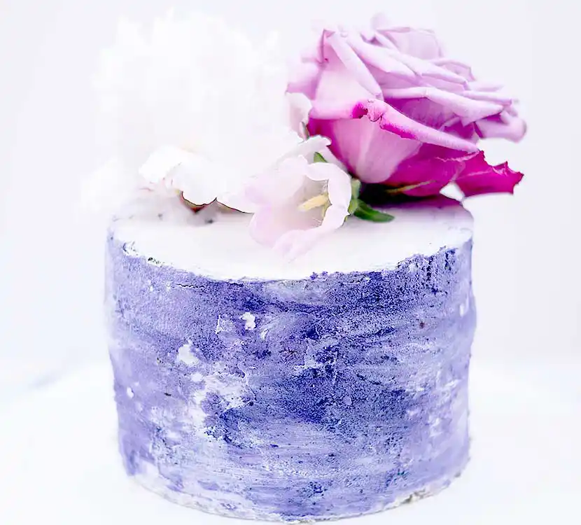 Blaue eingestrichene Torte mit Blumendeko.