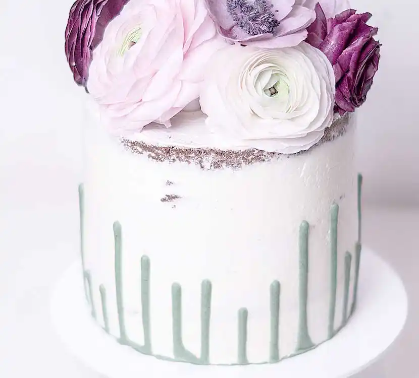 Teller mit mit weißer Torte und Upside Down Drip und Blumendeko.