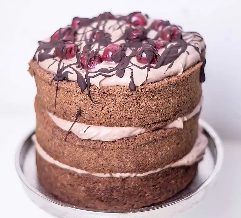 Teller mit dunkler Naked Torte und Kirschen.