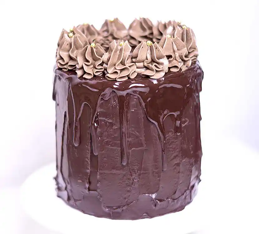 Teller mit dunkler Torte und Buttercreme-Deko.