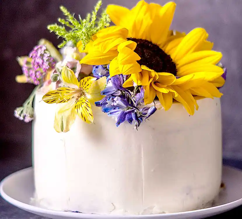 Teller mit weißer Torte und Sonnenblumendekor.